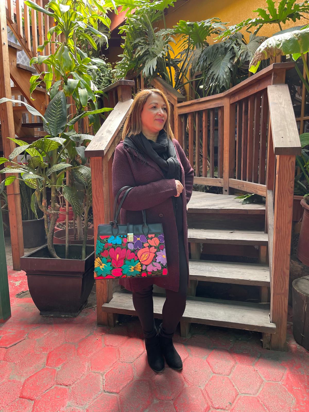 woman showcasing embroidered leather handbag