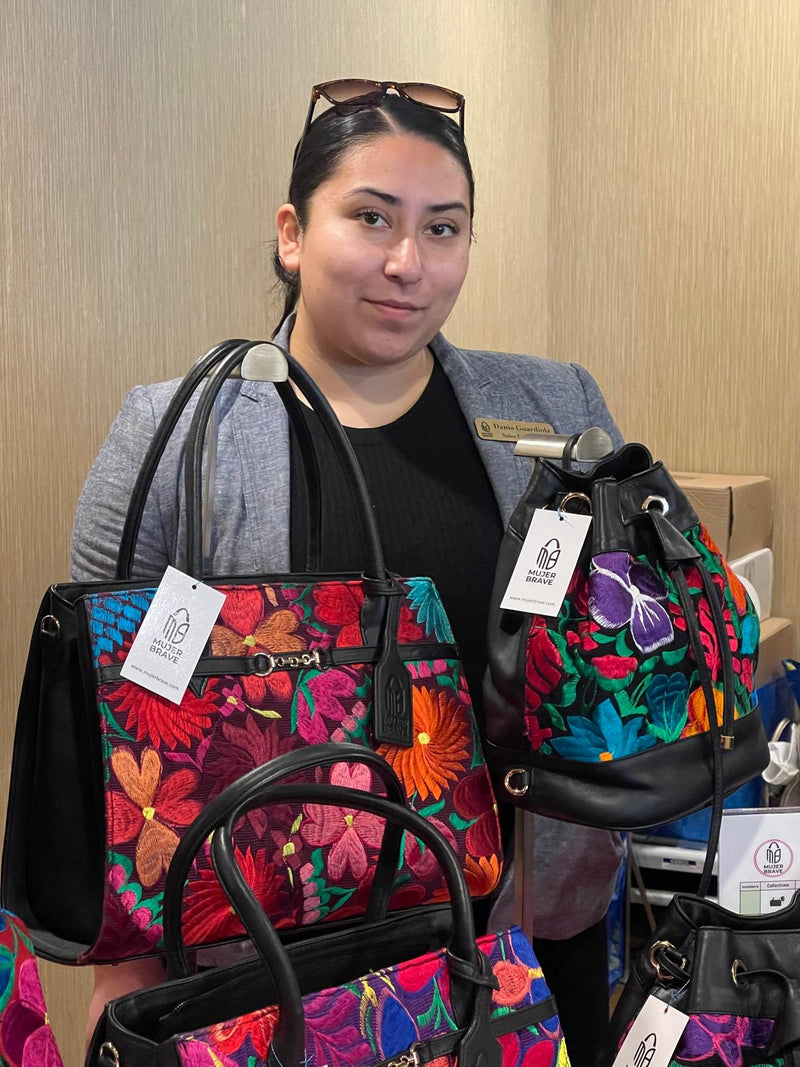 woman showcasing embroidered leather handbags