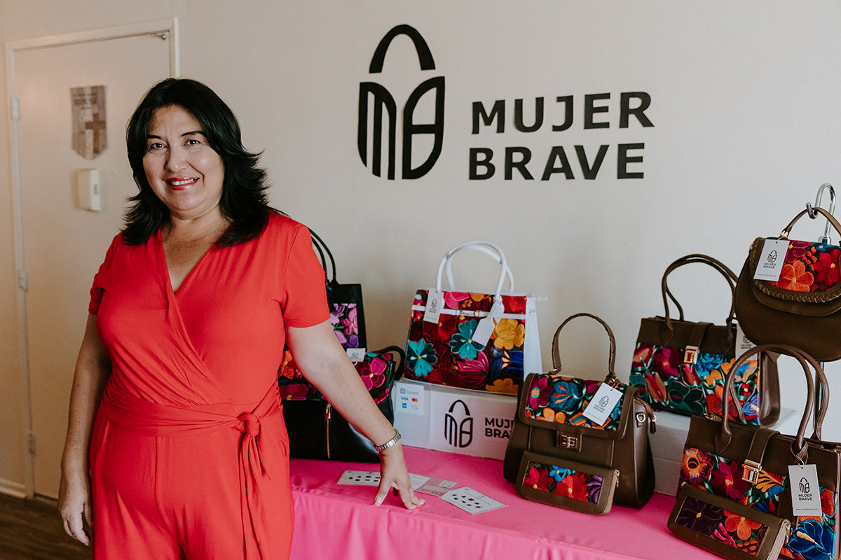 founder of mujer brave posing with bags and logo display